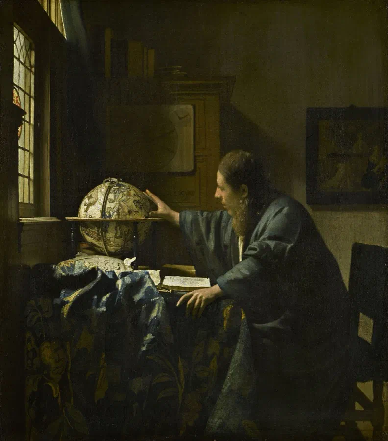 The Astronomer by Johannes Vermeer: a scholar at a desk turns a celestial globe with an open book before him, lit from a window on the left.